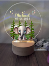 a personalized glass ornament with an elephant in a forest